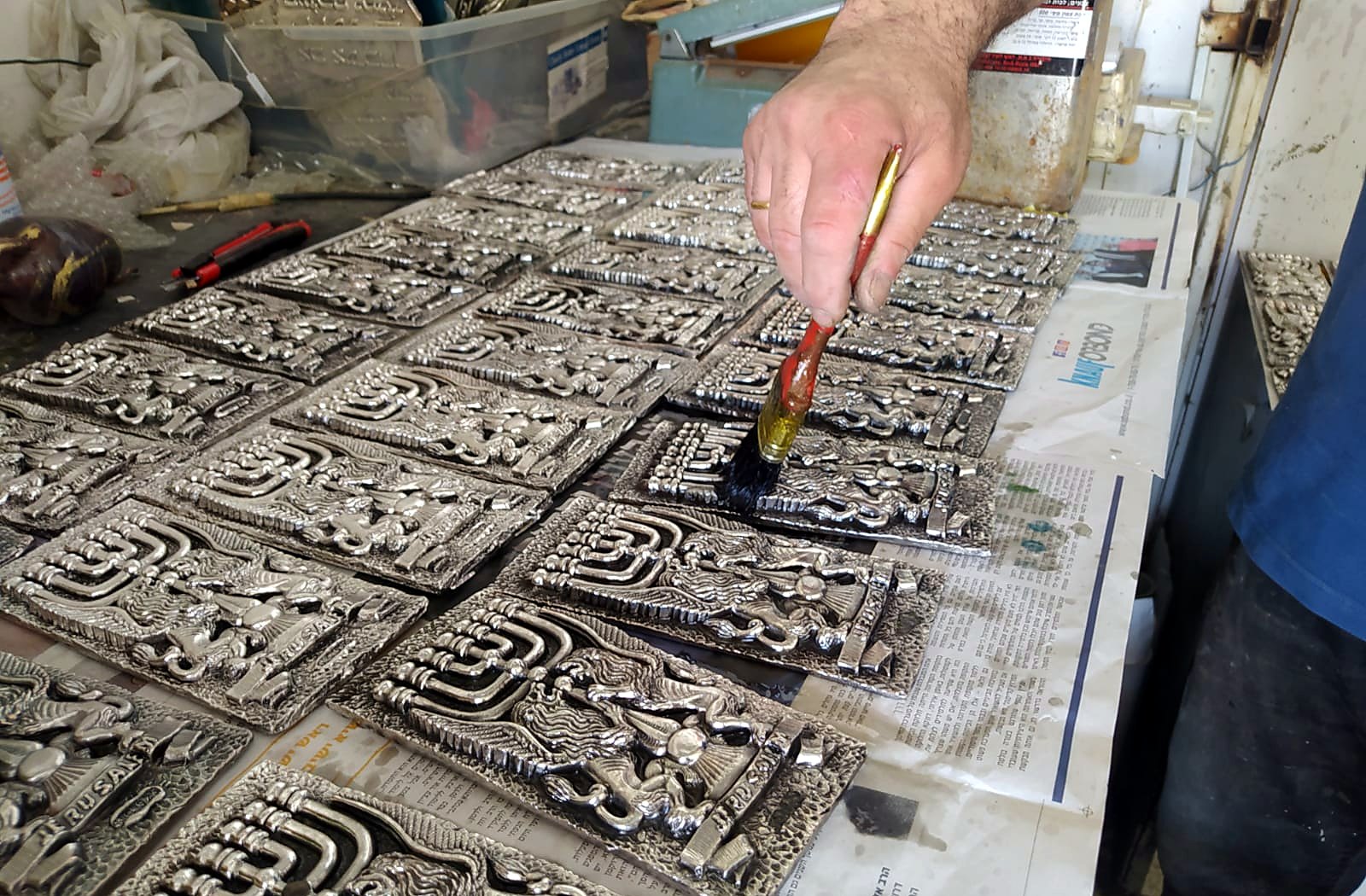 Artisan applying patina by hand to menorah reliefs in a Holy Land workshop