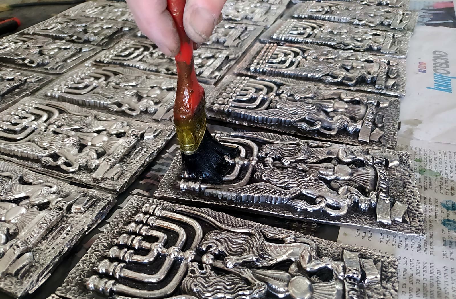 Close detail of hand-applied patina on a menorah relief