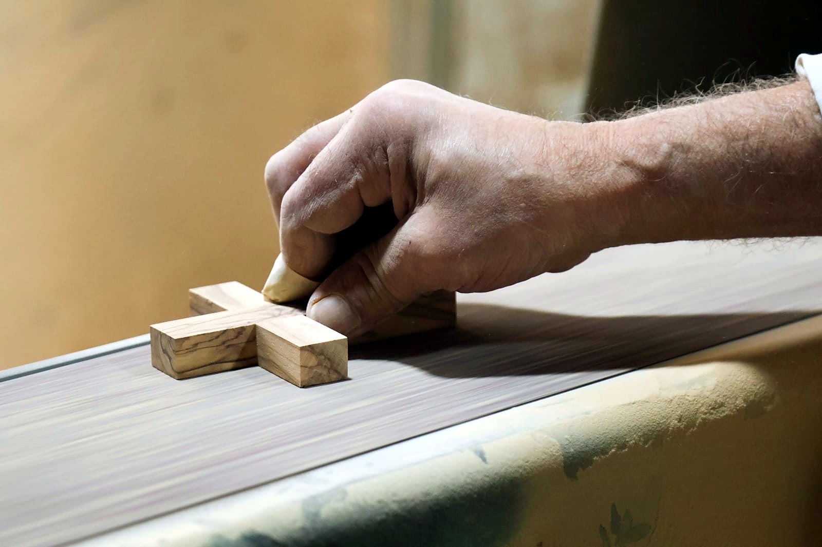 Sanding an olive wood cross by hand